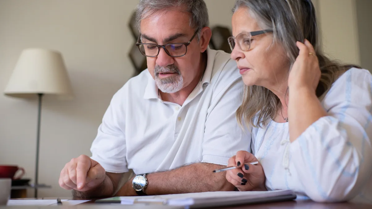 Older couple working on a crossword puzzle together at a table.