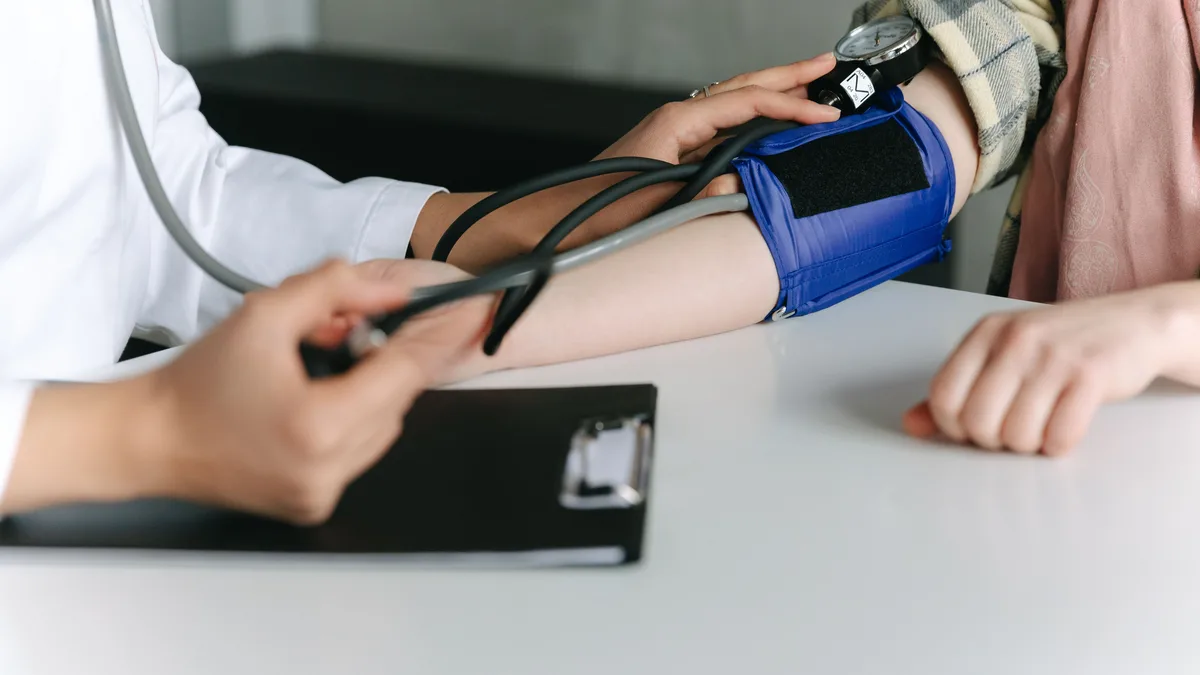 Healthcare worker measuring a patient's blood pressure with a cuff in a medical office.
