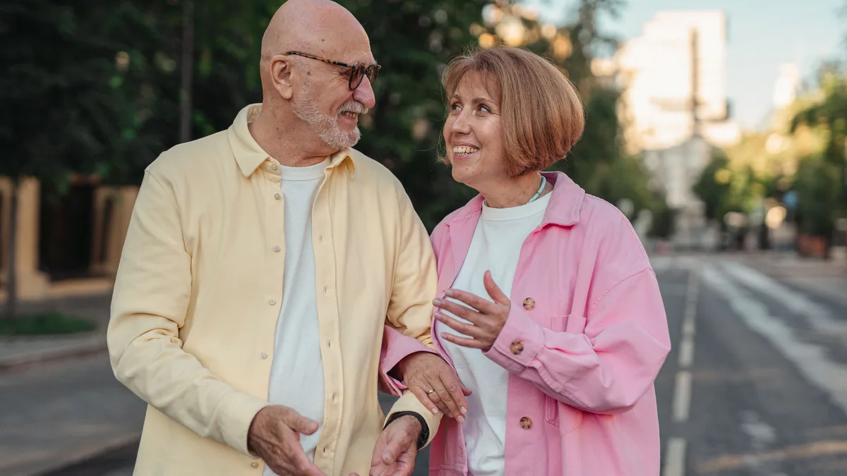 Older couple walking arm in arm along a city street.