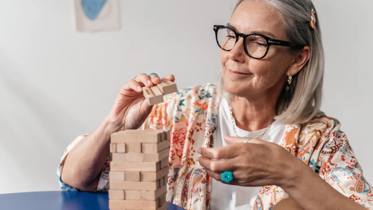 Older woman concentrating while stacking blocks in a tower game.