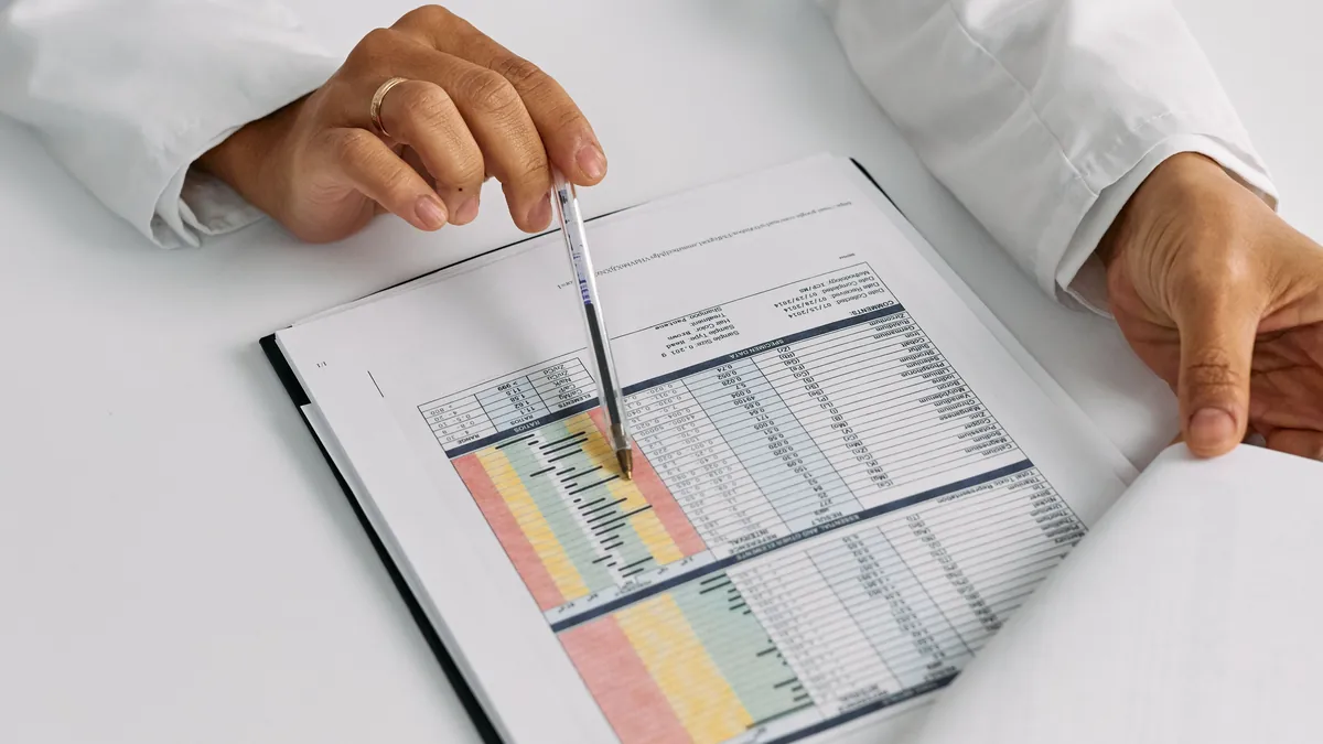 A clinician points a pen at a color-coded table of patient results