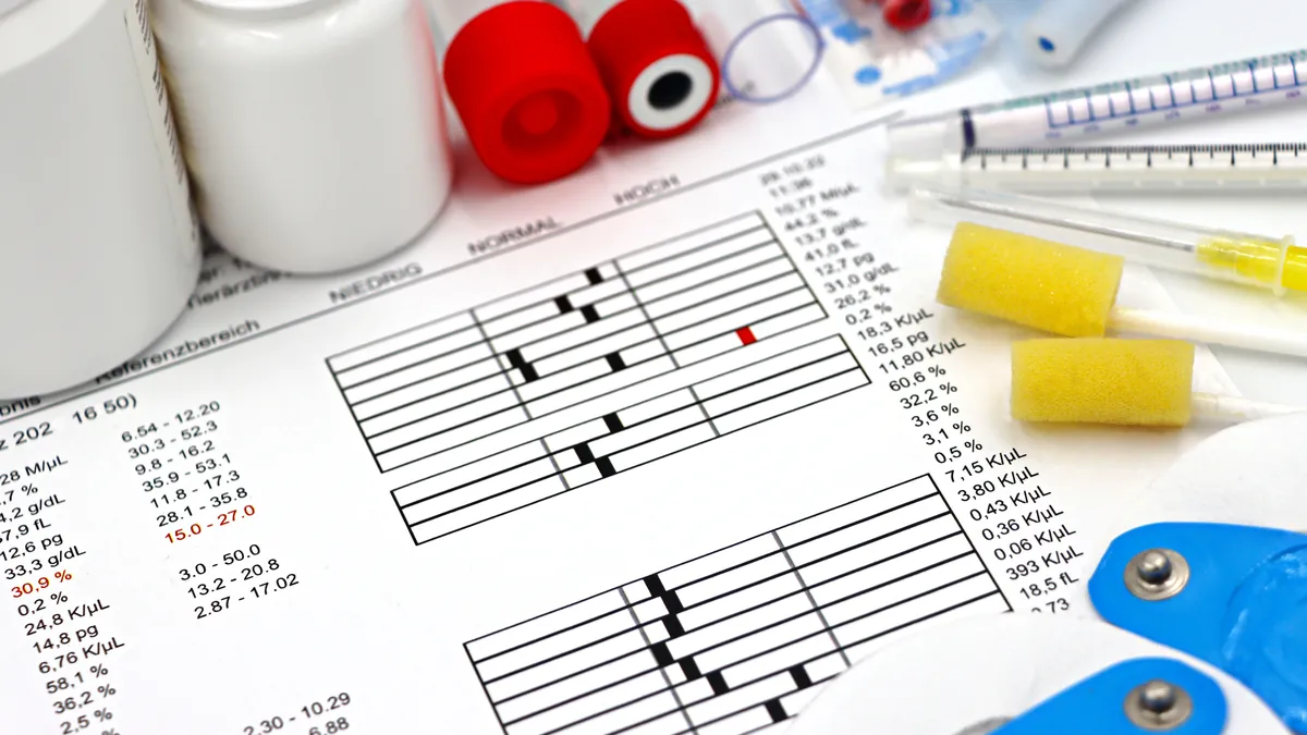 A printed lab report with reference ranges beside blood sample tubes
